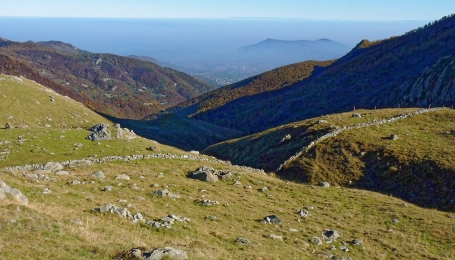 Muro in pietra che delimita i pascoli dell'Alpe di Giaveno inferiore, sullo sfondo la pianura coperta dallo smog